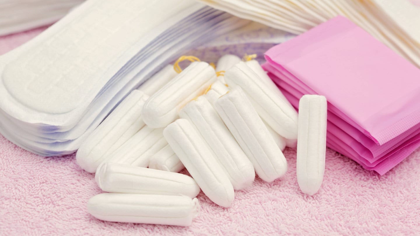 Tampons und Binden liegen auf einem Handtuch. Die Steuersenkung für die Periodenprodukte wurde laut einer Studie an Verbraucherinnen weitergegeben