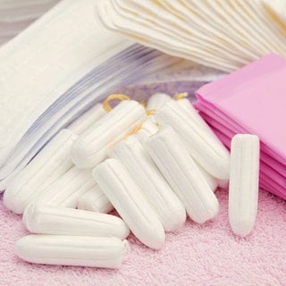 Tampons und Binden liegen auf einem Handtuch. Die Steuersenkung für die Periodenprodukte wurde laut einer Studie an Verbraucherinnen weitergegeben