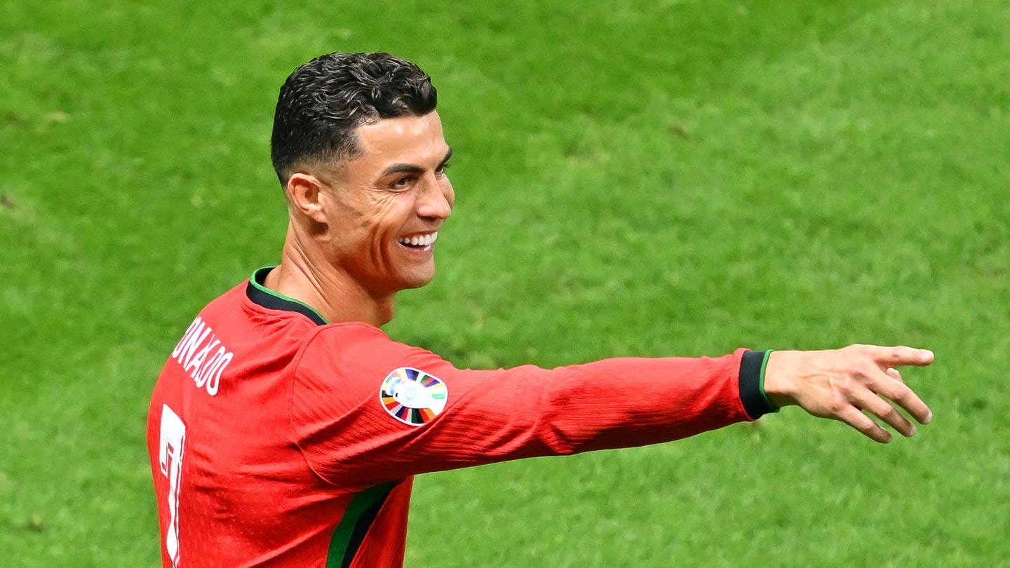 Portugals Cristiano Ronaldo steht auf dem Spielfeld und zeigt lachend mit seiner Hand in eine Richtung. Der Fußball-Star hat mit seinem YouTube-Account einen Follower-Rekord geknackt.