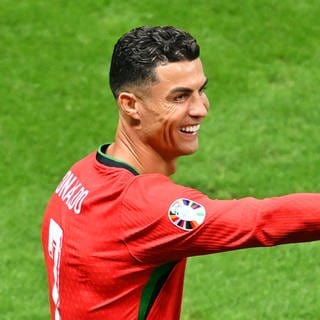 Portugals Cristiano Ronaldo steht auf dem Spielfeld und zeigt lachend mit seiner Hand in eine Richtung. Der Fußball-Star hat mit seinem YouTube-Account einen Follower-Rekord geknackt.