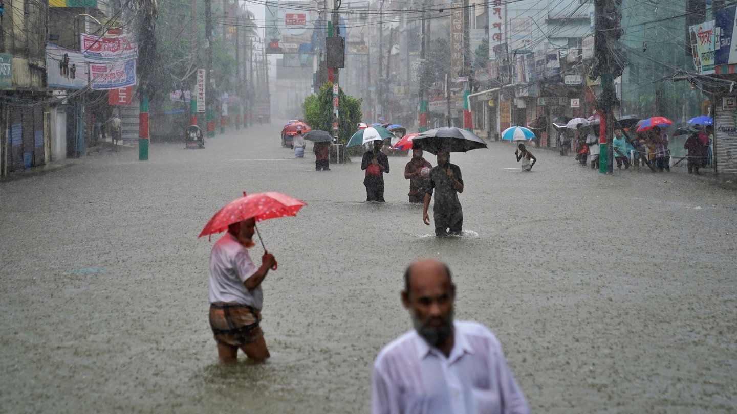 Menschen gehen durch eine überschwemmte Straße nach anhaltenden Regenfällen in Feni, einem Küstenbezirk im Südosten Bangladeschs an der Grenze zum indischen Bundesstaat Tripura.