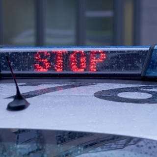 Der Schriftzug "Stop" ist neben dem Blaulicht auf dem Dach eines Polizeiautos zu lesen.