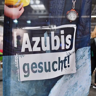 "Azubis gesucht" steht auf einer Fahne. Viele junge menschen suchen Ausbildungsplätze - da sliegta uch an der Suche der Unternehmen auf den falschen Social-Media-Plattformen