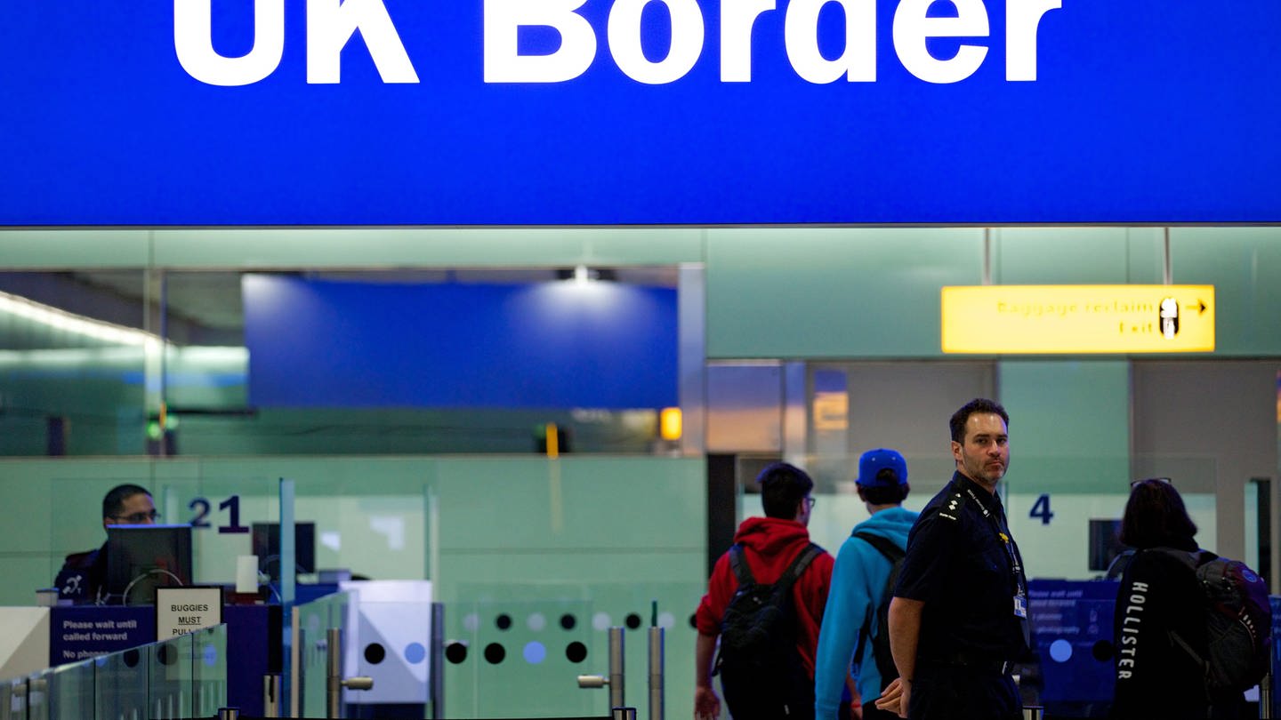 Grenzbeamte stehen am Flughafen Heathrow unter einem Schild mit der Aufschrift «UK Border».