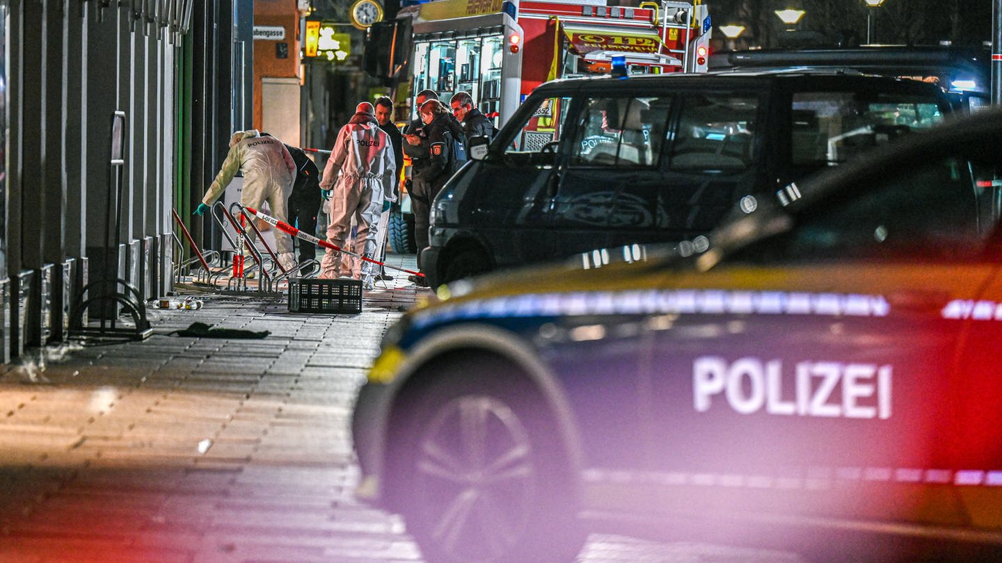 Mitarbeiter der Spurensicherung und der Polizei stehen nach der Geiselnahme in Ulm im abgesperrten Bereich in der Nähe des Münsterplatzes.