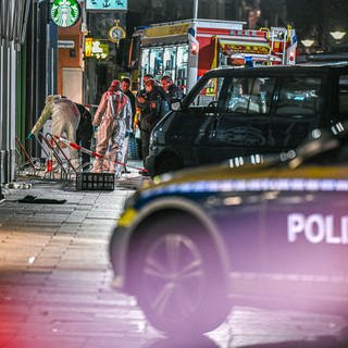 Mitarbeiter der Spurensicherung und der Polizei stehen nach der Geiselnahme in Ulm im abgesperrten Bereich in der Nähe des Münsterplatzes.