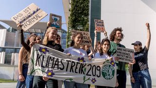 Mitglieder von Fridays for Future Deutschland halten vor dem Bundeskanzleramt bei einer Pressekonferenz zum geplanten globalen Klimastreik am 20. September 2024 ein Transparent mit der Aufschrift "Klimastreik 20.9."