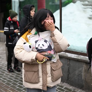 (Symbolbild) Eine Besucherin in einem chinesischen Zoo reagiert beim Anblick eines Panda-Babys.