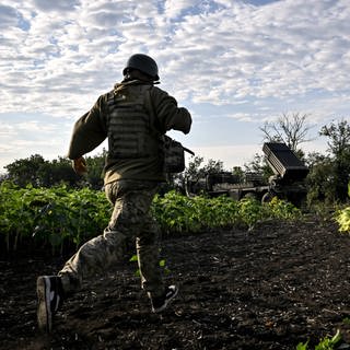 Ukrainischer Soldat läuft über ein Feld mit Sonnenblumen: Wenn sie sich ergeben werden sie von russischen Soldaten häufig erschossen.