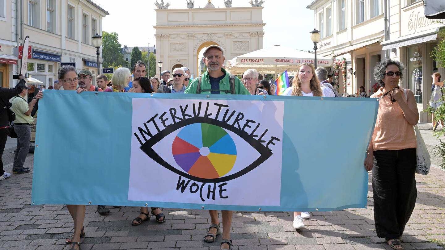 Eine Gruppe hält vor dem Brandenburger Tor ein Banner mit 