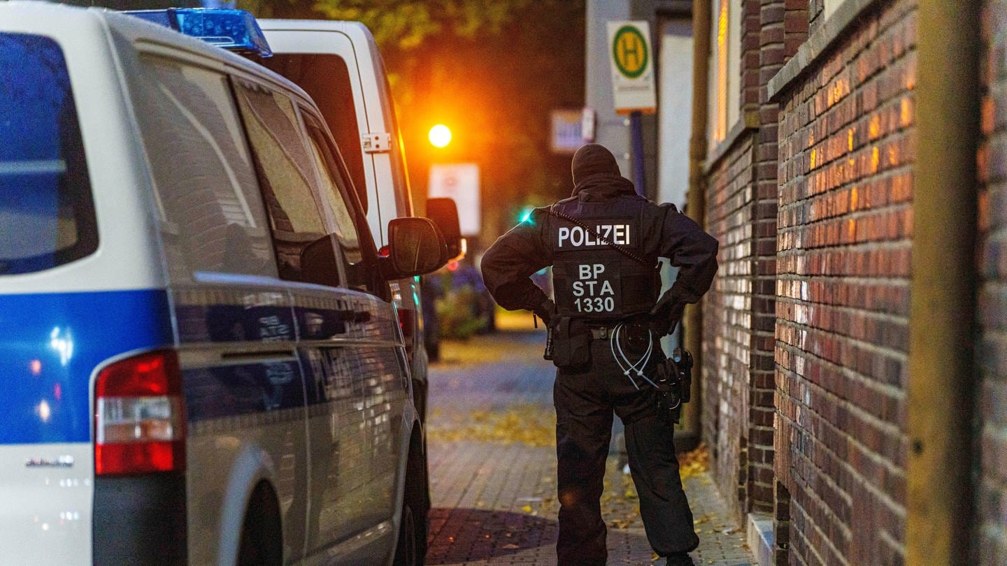 In der Waldhofstraße in Mannheim stehen Polizeikräfte vor einem Objekt im Zusammenhang mit einer Razzia wegen Schleuserkriminalität