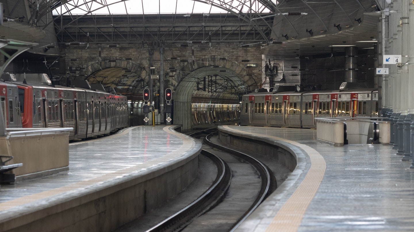 Leerer Bahnhof mit einfahrenden Zügen in Portugal.