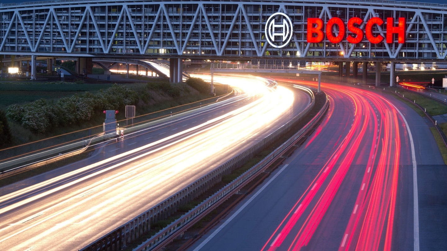 Das Bosch-Logo an einer Autobahnbrücke, Autos fahren darunter entlang.