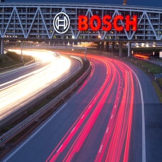 Das Bosch-Logo an einer Autobahnbrücke, Autos fahren darunter entlang.