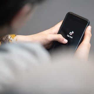 Eine Jugendliche schaut auf ihrem Handy TikTok. Dort gehen gerade KI-generierte Hitler-Videos viral