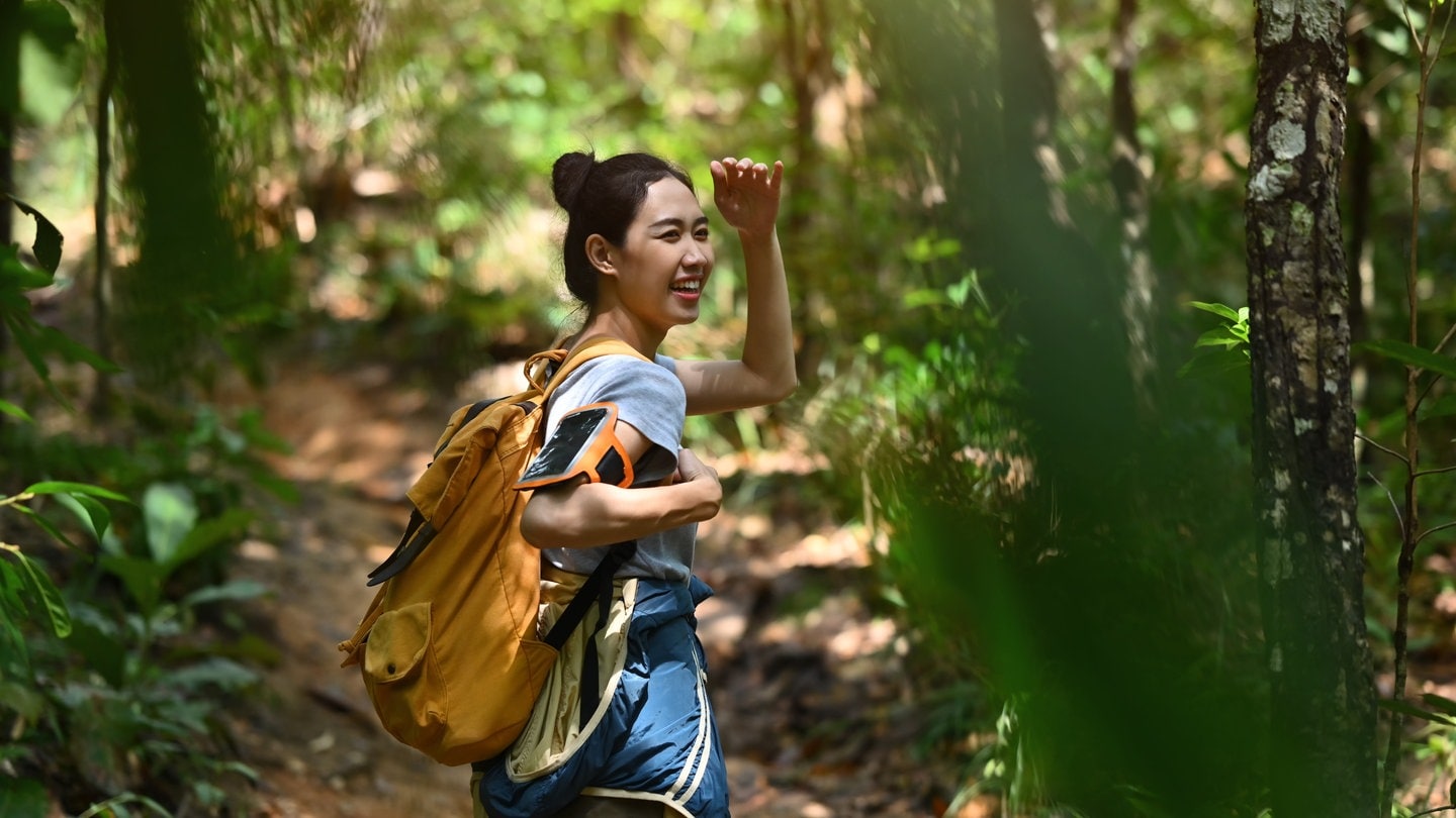 Eine junge Frau, lachend, mit einem Rucksack auf Backpacking-Trip