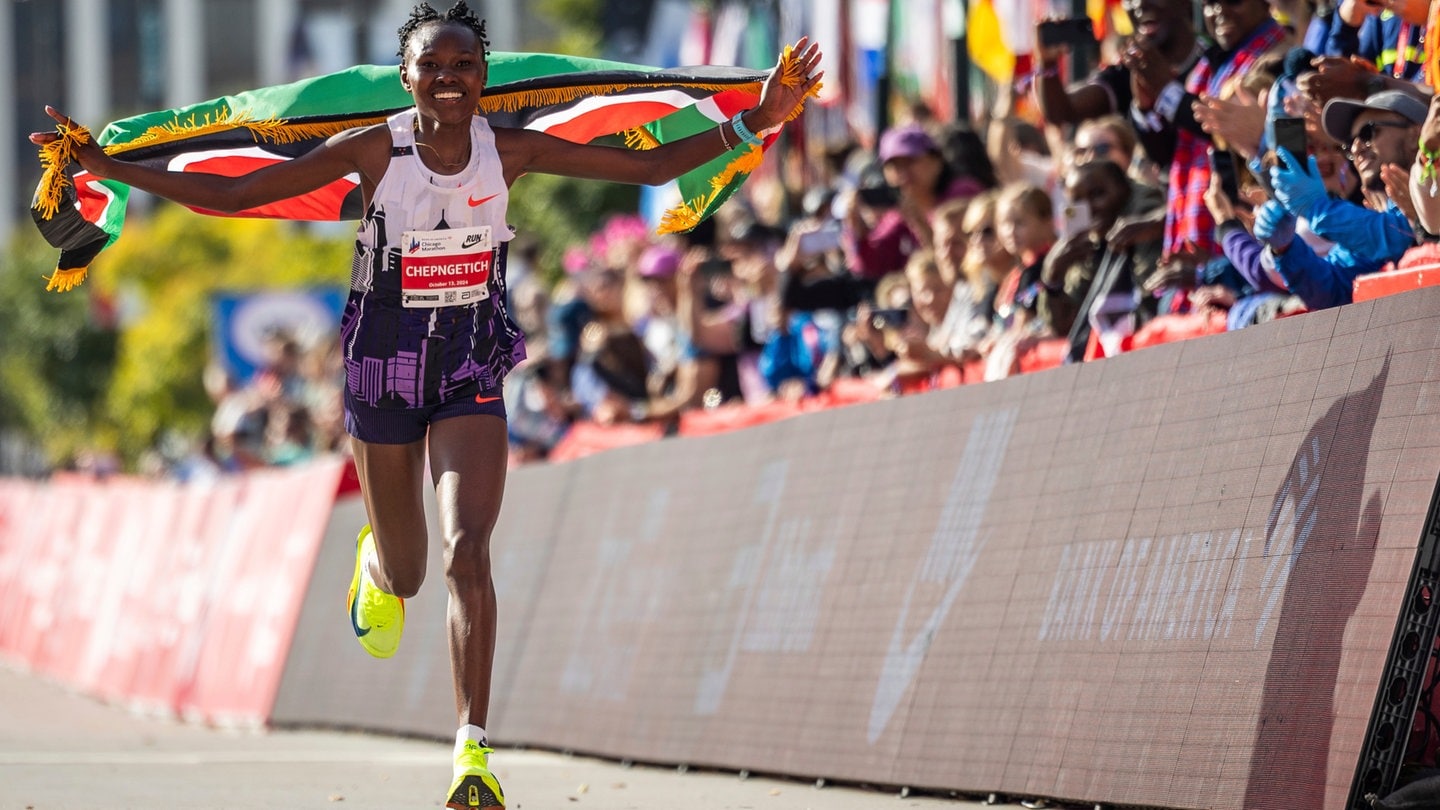 Ruth Chepngetich aus Kenia läuft mit der kenianischen Fahne, nachdem sie die Ziellinie als Siegerin überquert hat und den Marathon-Weltrekord der Frauen gebrochen hat.