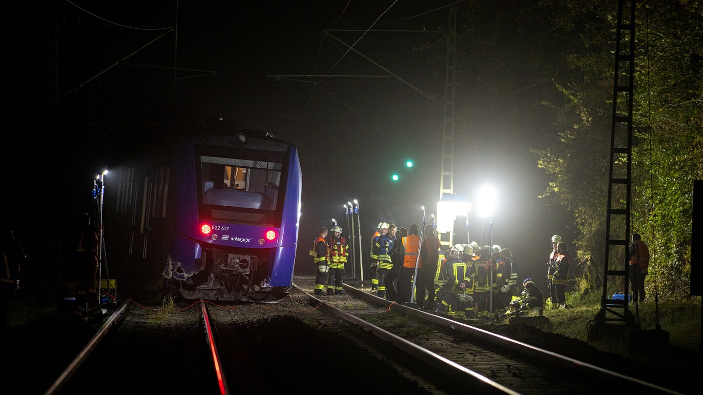 Feuerwehrleute arbeiten an einem Regionalexpress des Unternehmens vlexx. Der Regionalzug war gegen einen großen Felsbrocken auf den Gleisen geprallt und auf offener Strecke entgleist.