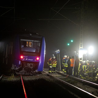 Feuerwehrleute arbeiten an einem Regionalexpress des Unternehmens vlexx. Der Regionalzug war gegen einen großen Felsbrocken auf den Gleisen geprallt und auf offener Strecke entgleist.