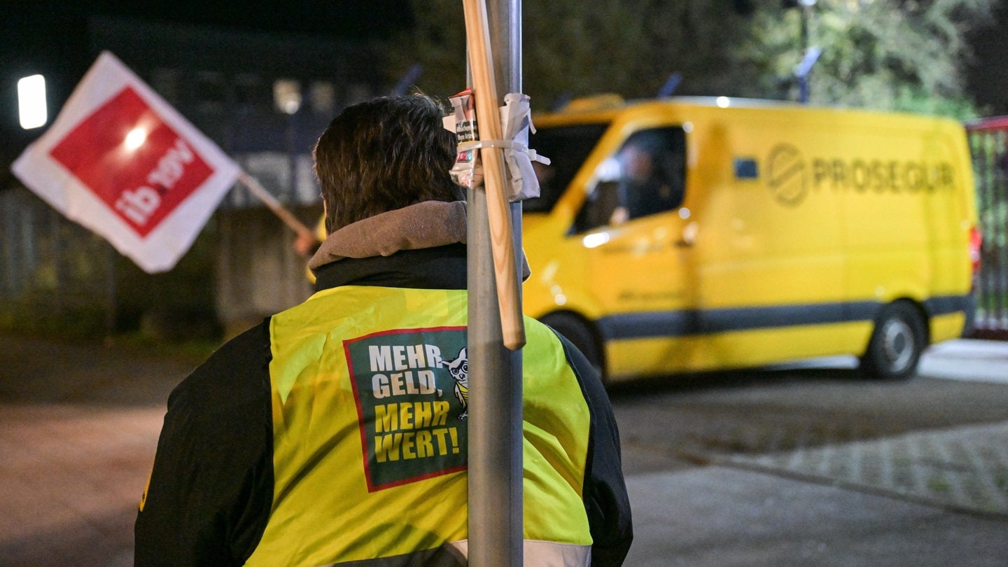 Ein Streikender trägt eine Weste mit der Aufschrift «Mehr Geld - Mehr Wert». Im Hintergrund steht ein Geldtransporter der Firma Prosegur. Die Gewerkschaft Verdi ruft Beschäftigte des Geld- und Werttransportes zu ganztägigen Warnstreiks in allen Bundesländern auf.