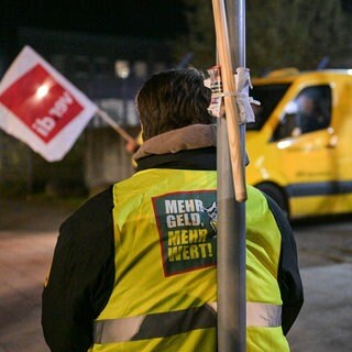 Ein Streikender trägt eine Weste mit der Aufschrift «Mehr Geld - Mehr Wert». Im Hintergrund steht ein Geldtransporter der Firma Prosegur. Die Gewerkschaft Verdi ruft Beschäftigte des Geld- und Werttransportes zu ganztägigen Warnstreiks in allen Bundesländern auf.