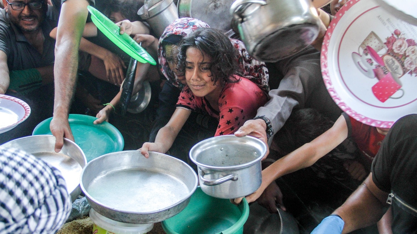 Kinder strecken ihre Gefäße aus, um im nördlichen Gazastreifen Essen zu bekommen. Israel soll jetzt die Hilfe für Gaza wieder stärker durchlassen - viele Kinder leiden an Mangelernährung.