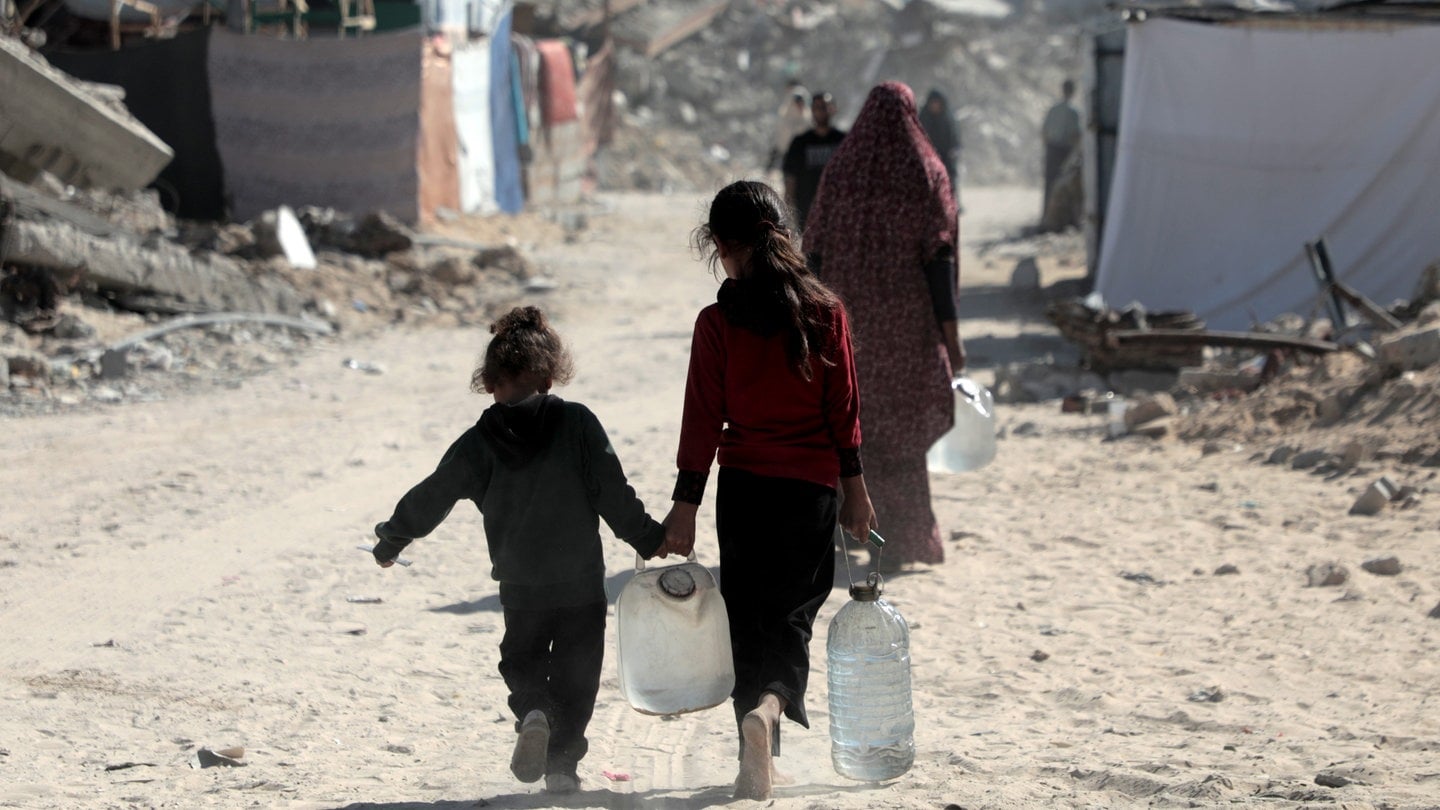 Kinder im Gazastreifen kehren in der Stadt Chan Junis im südlichen Gazastreifen nach Hause zurück, nachdem sie Flaschen mit Wasser gefüllt haben.