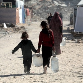 Kinder im Gazastreifen kehren in der Stadt Chan Junis im südlichen Gazastreifen nach Hause zurück, nachdem sie Flaschen mit Wasser gefüllt haben.