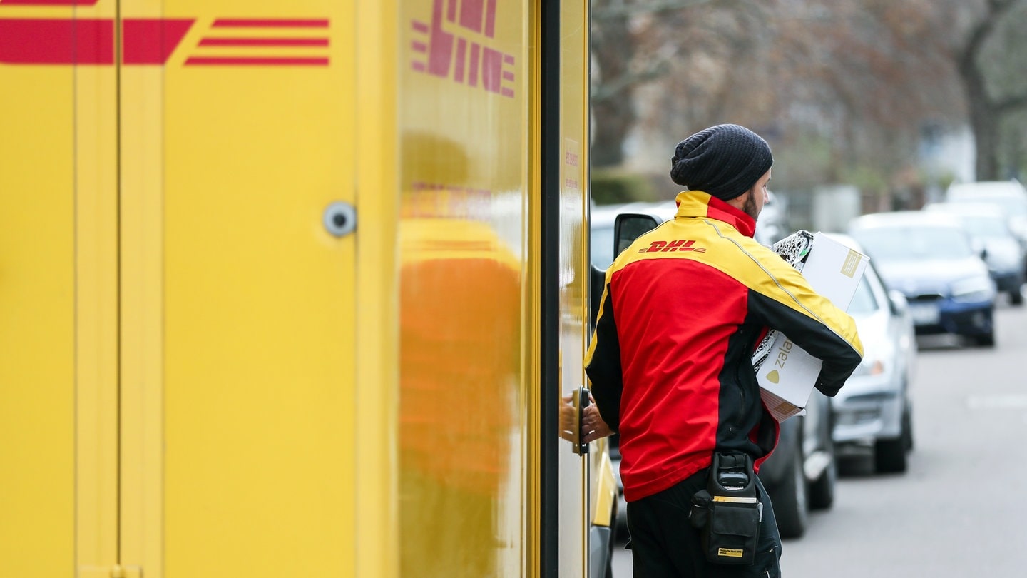 Ein DHL-Paketzusteller verlässt mit mehreren Sendungen sein Fahrzeug - Immer mehr Attacken gegen Paket-Zusteller