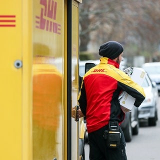 Ein DHL-Paketzusteller verlässt mit mehreren Sendungen sein Fahrzeug - Immer mehr Attacken gegen Paket-Zusteller