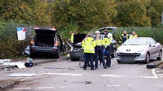 Einsatzkräfte der Polizei stehen an der Unfallstelle in Esslingen am Neckar neben drei Fahrzeugen. Bei dem schweren Verkehrsunfall sind nach Polizeiangaben drei Personen gestorben.