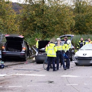 Einsatzkräfte der Polizei stehen an der Unfallstelle in Esslingen am Neckar neben drei Fahrzeugen. Bei dem schweren Verkehrsunfall sind nach Polizeiangaben drei Personen gestorben.