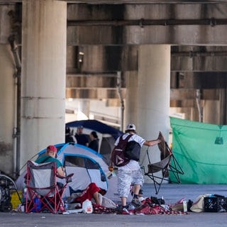 Menschen, die in einem Obdachlosenlager leben, heben ihre Habseligkeiten auf, nachdem die Polizei des Bundesstaates Louisiana sie angewiesen hat, sich an einen anderen, vorher festgelegten Ort zu begeben, während sie eine Razzia im Vorfeld eines Taylor Swift-Konzerts durchführt.