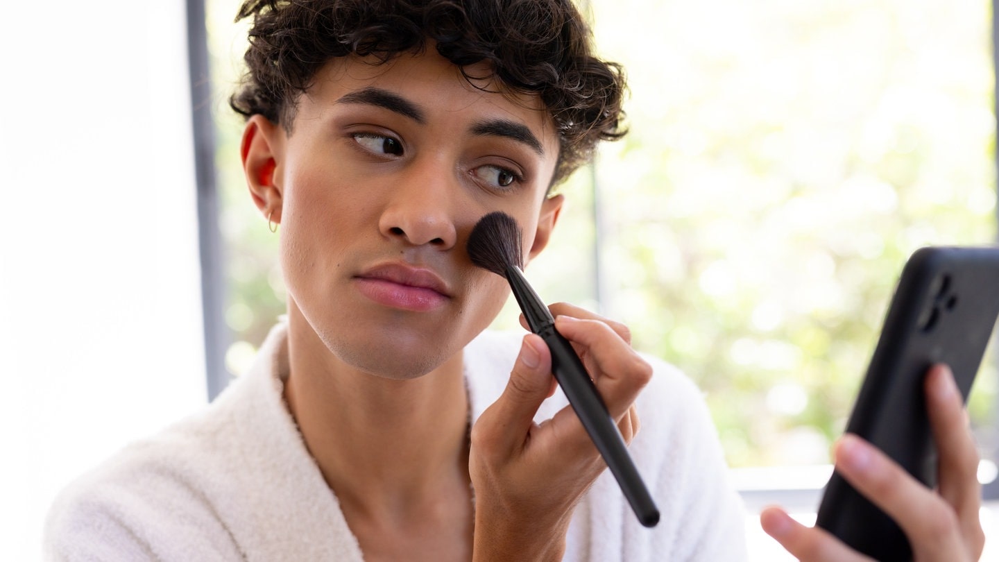 Eine Trans-Frau trägt Make-Up auf.