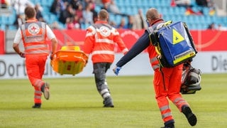 Sanitäter laufen über das Spielfeld (Symbolbild)