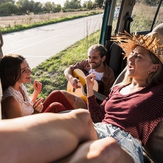 Eine Gruppe sitzt glücklich miteinander in einem Bus.