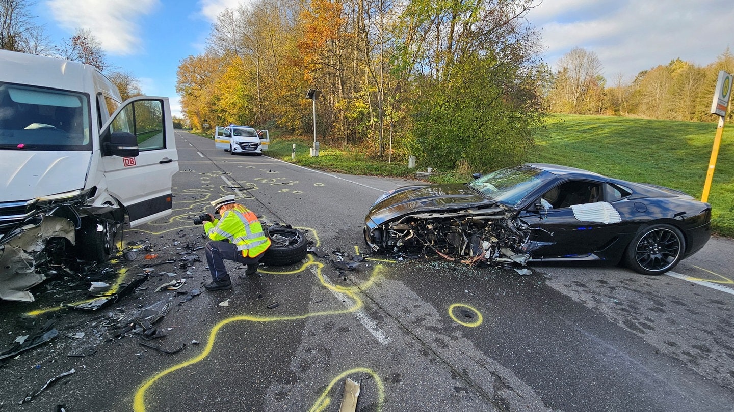 Ein schwer beschädigter Ferrari steht nach einem Unfall mit einem Lieferwagen auf einer Straße.