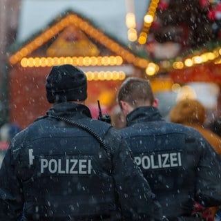 Zwei Polizisten gehen Streife auf dem Weihnachtsmarkt. 