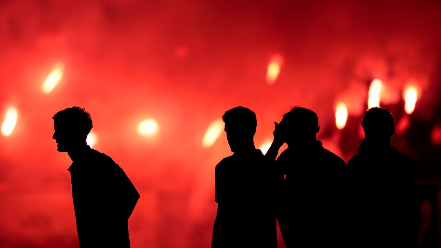 Menschen vor rotem Bengalo-Feuer: Pyrotechnik vor der Arena in Trier sorgt für späten Spielstart im Basketball 2. Liga.