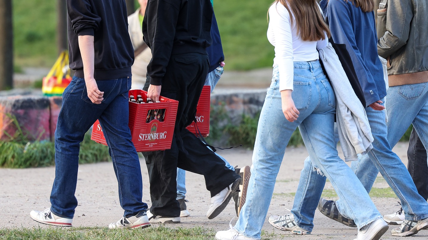 Eine Gruppe junger Erwachsener trägt Bierkästen durch den Mauerpark.