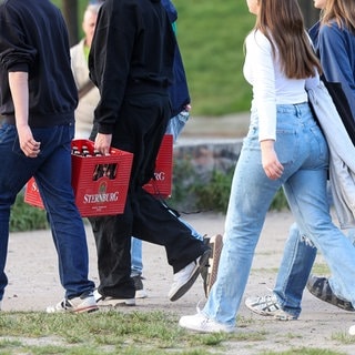 Eine Gruppe junger Erwachsener trägt Bierkästen durch den Mauerpark.