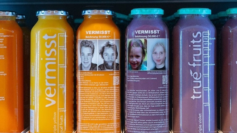 Zwei Smoothie-Flaschen von True Fruits, auf denen Bilder von den vermissten Menschen Lars Mittank und Inga Gehricke aufgedruckt sind.