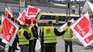 Mitarbeiter der Südwestdeutschen Landesverkehrs GmbH (SWEG) stehen bei einer Kundgebung im Rahmen eines Warnstreiks auf vor dem Bahnhof in Gammertingen. 