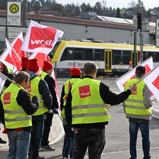 Mitarbeiter der Südwestdeutschen Landesverkehrs GmbH (SWEG) stehen bei einer Kundgebung im Rahmen eines Warnstreiks auf vor dem Bahnhof in Gammertingen. 