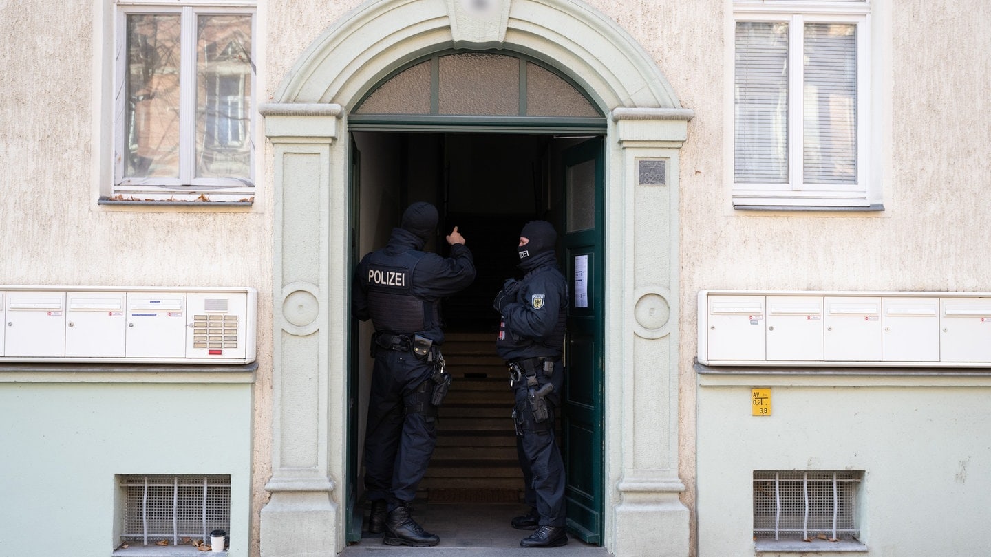 Polizisten stehen während einer Razzia gegen mutmaßliche Rechtsextreme in einem Hauseingang im Dresdner Stadtteil Cotta.