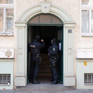 Polizisten stehen während einer Razzia gegen mutmaßliche Rechtsextreme in einem Hauseingang im Dresdner Stadtteil Cotta. 