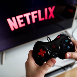 Ein Controller vor einem Bildschirm der das Netflix-Logo zeigt.