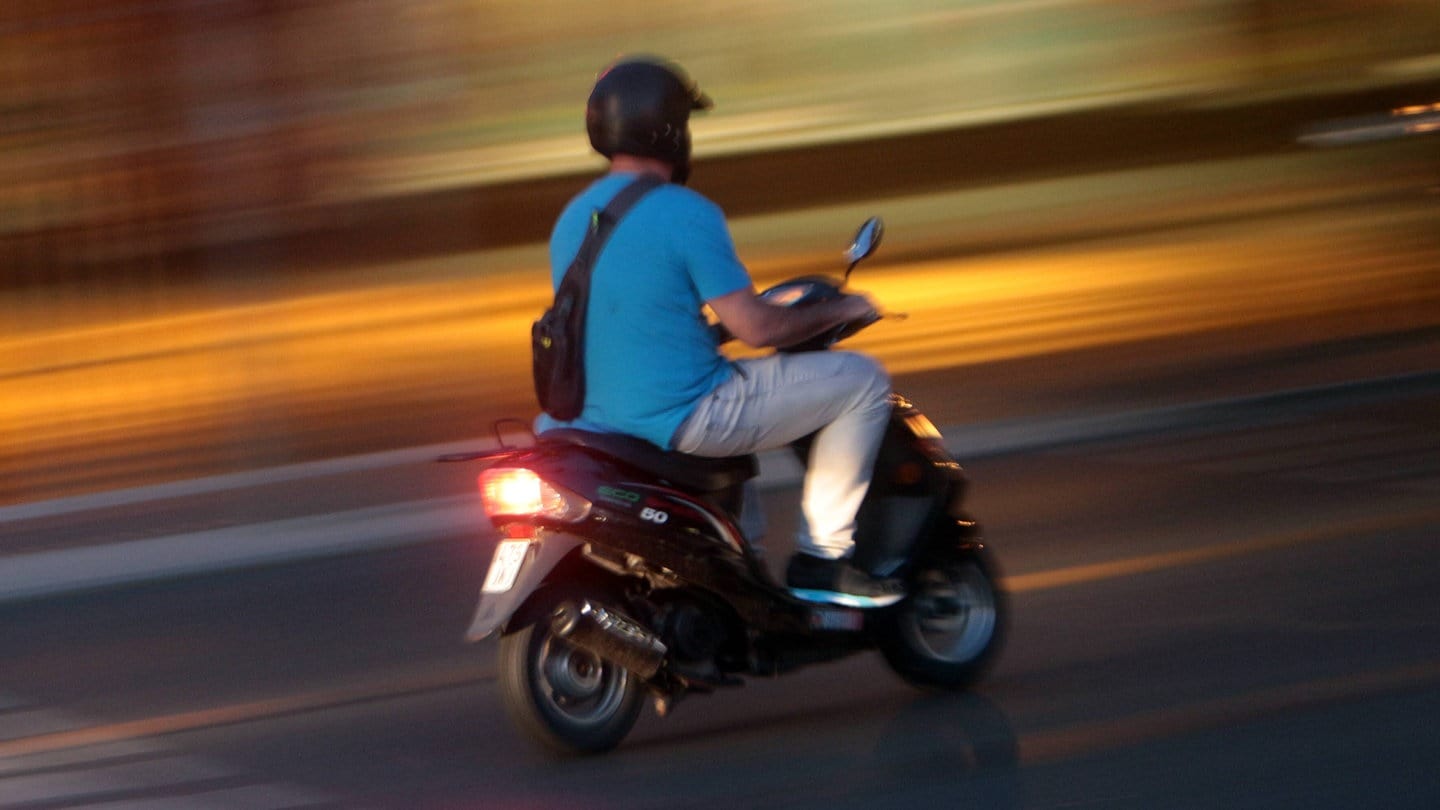 Eine Person fährt einen Motorroller in der Abenddämmerung. (Symbolbild)