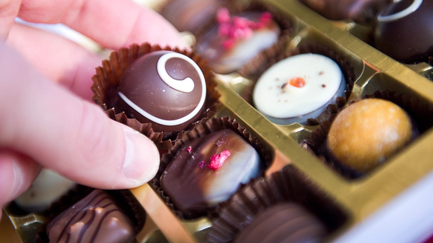 Eine Praline aus einer aufgeklappten Pralinenschachtel: Ein Mann, der mit Alkohol am Steuer erwischt wurde, sagt: Er habe versehentlich Schnaps-Pralinen gegessen.