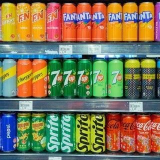 Getränkedosen in einem Supermarkt Kühlregal von Coca Cola, Sprite, Pepsi, Schweppes und Fanta